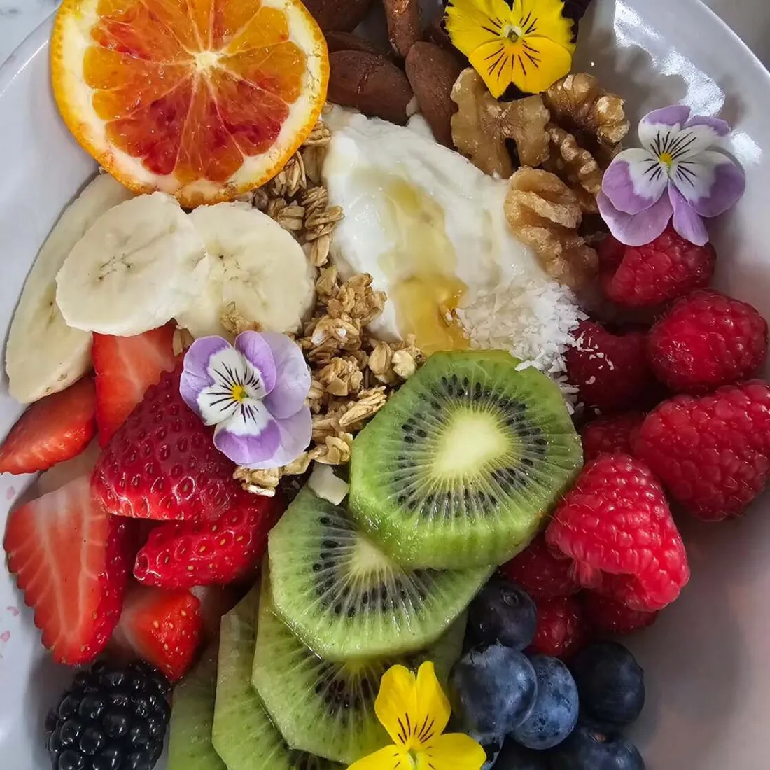A brunch plate of fruit, egg, granola and edible flowers