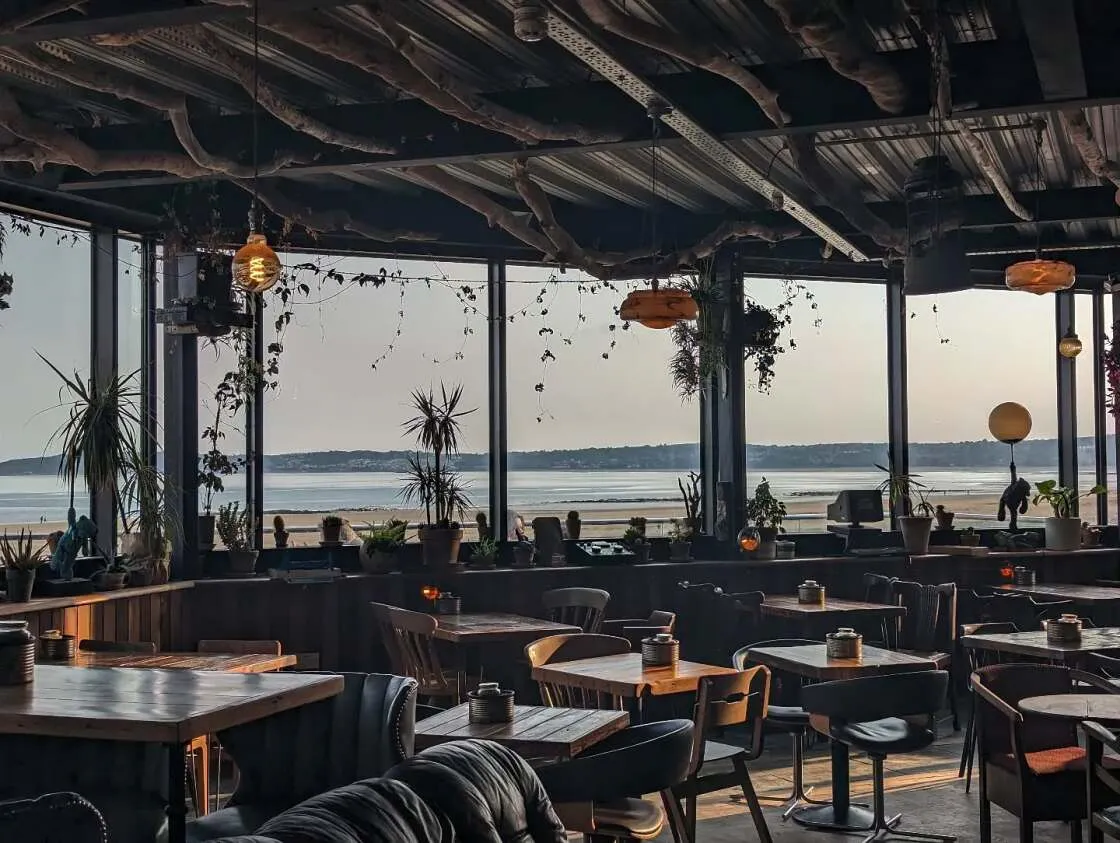 Inside The Observatory, tables by tall windows looking out across Swansea Bay